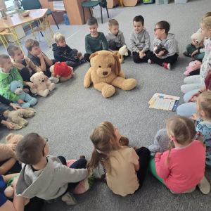 Dzieci siedzą w kole z misiami