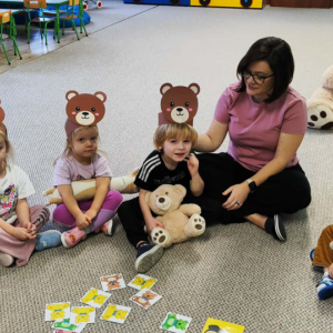 Dzieci siedzą na dywanie z misiami