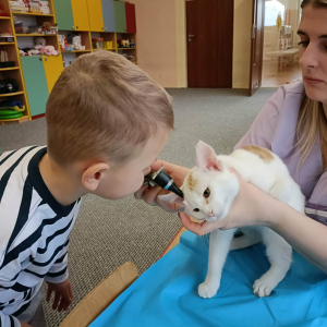 Dziecko zagląda do ucha kota