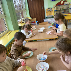 Dzieci siedzą przy stoliku i dekorują pierniki