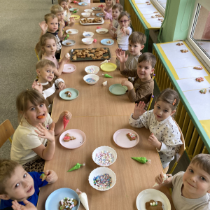 Dzieci siedzą przy stoliku i dekorują pierniki