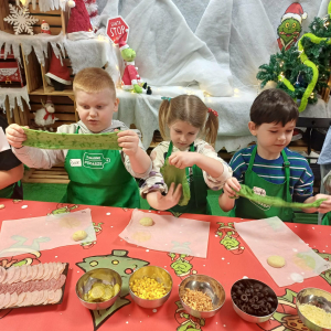Dzieci ugniatają i formują ciasto na pizze.