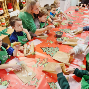 Dzieci nadziewają choinki kremem pistacjowym.