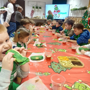 Dzieci jedzą własnoręcznie zrobioną pizze i popijają ją herbatką zimową.