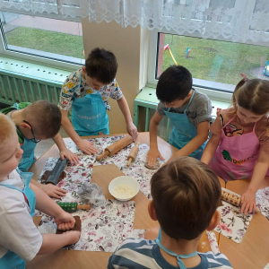 Dzieci wałkuja ciasto na pierniczki.