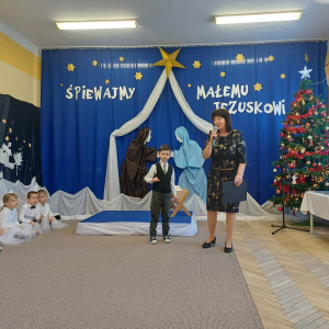 Chłopiec stoi przed scena z organizatorką przeglądu