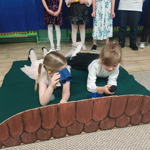 Dziewczynki leżą na "dachu" i patrzą przez lornetki