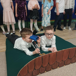 Chłopcy leżą na "dachu" i patrzą przez lornetkę 