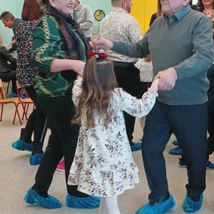 Dziadkowie i dzieci tańczą.