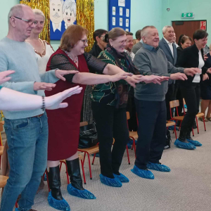 Dziadkowie stoją i naśladują ruchy z zabawy.