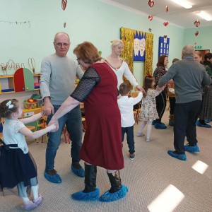 Dziadkowie i dzieci tańczą.