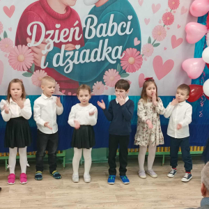 Dzieci stoją na tle dekoracji.