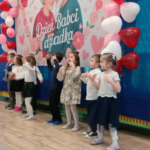 Dzieci stoją na tle dekoracji.