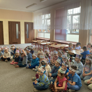 Dzieci siedzą na dywanie i oglądają film