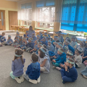 Dzieci siedzą na dywanie i oglądają film