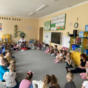 Dzieci siedzą w kole z panią pielęgniarką