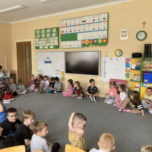 Dzieci siedzą w kole z panią pielęgniarką