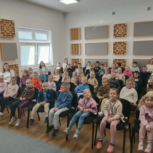 Dzieci siedzą na krzesełkach i oglądają występ