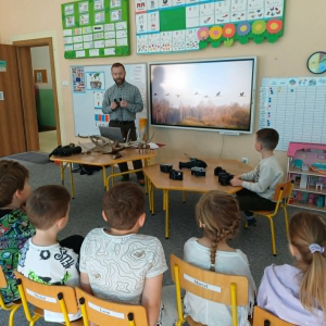 Dzieci siedzą na krzesłach a Pan Hubert opowiada o zwyczajach zwierząt