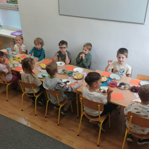 Dzieci siedzą przy stoliku i jedzą przekąski