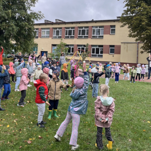 Dzieci tańczą na trawie w rytm muzyki z instruktorem tańca