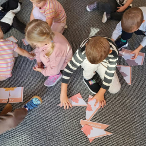 Dzieci na dywanie układają jesienne puzzle