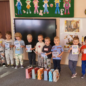 Chłopcy stoją z dyplomami i prezentami.