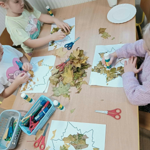 Dzieci wykonują prace plastyczną darami natury - liśćmi
