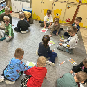 Dzieci siedzą na dywanie i układają puzzle związane z drzewami