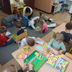 Dzieci graja w gry na dywanie i przy stolikach