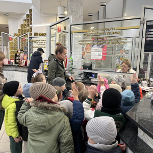 Dzieci stoją przy okienku w urzędzie pocztowym