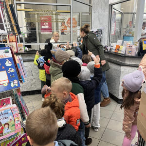 Dzieci stoją przy okienku urzędu pocztowego