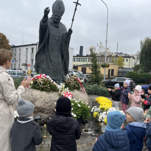 Dzieci modlą się  przed pomnikiem Papieża 