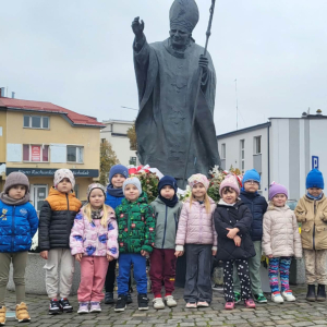 Dzieci stoją przed pomnikiem Papieża 